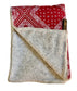 Folded blanket with red bandana pattern on one side and gray fleece on the other, on a light background.